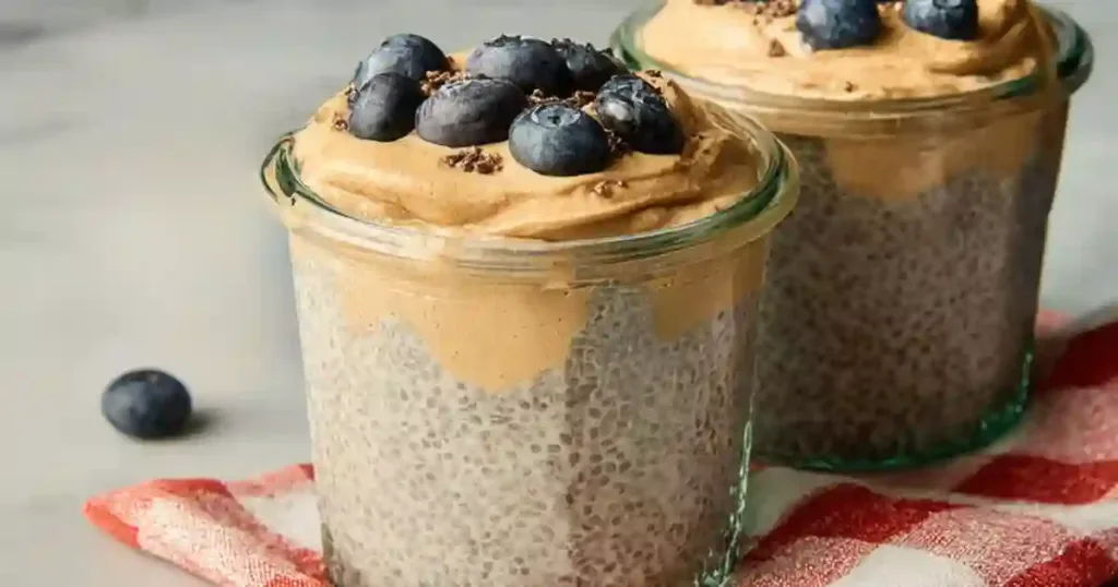 Peanut Butter Chia Pudding 1 Peanut butter chia pudding in a clear jar with fresh berries and cacao nibs on top