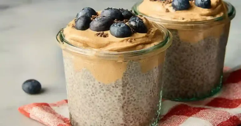 Peanut butter chia pudding in a clear jar with fresh berries and cacao nibs on top